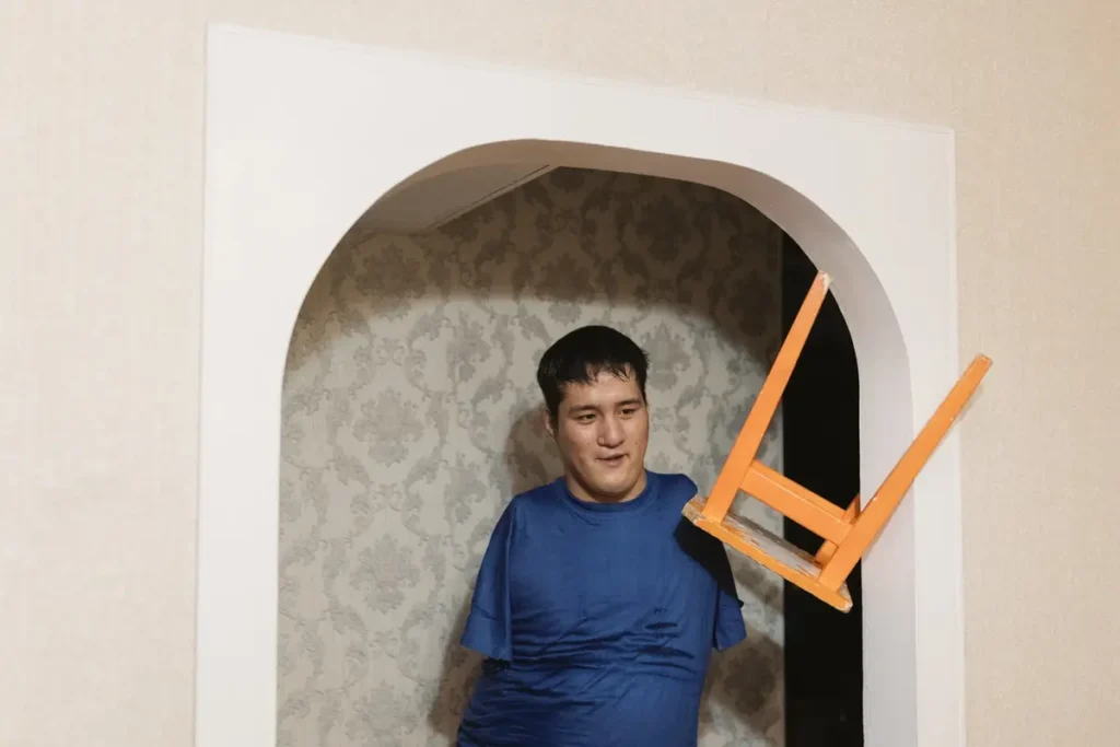 Серик Отынчинов переносил табурет на&nbsp;кухню и&nbsp;остановился, чтобы поговорить с&nbsp;двумя друзьями из&nbsp;интерната, с&nbsp;которыми он&nbsp;арендует квартиру в&nbsp;Омске, январь 2022. Фото: Вадим Брайдов.